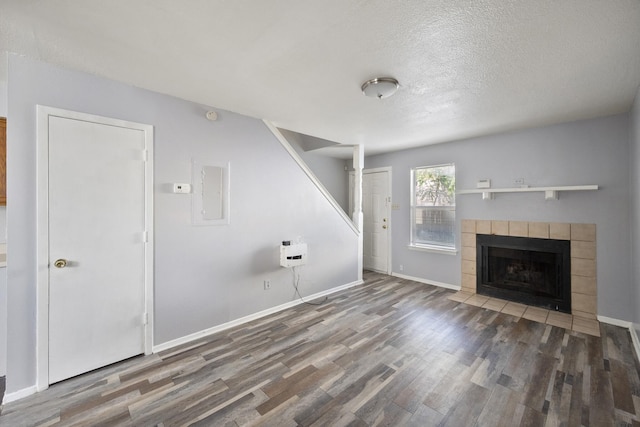 unfurnished living room with baseboards, a fireplace, a textured ceiling, and wood finished floors