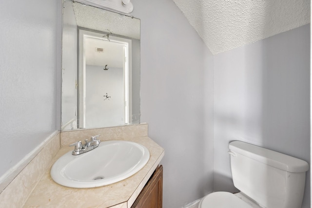 bathroom featuring vanity, a textured ceiling, and toilet