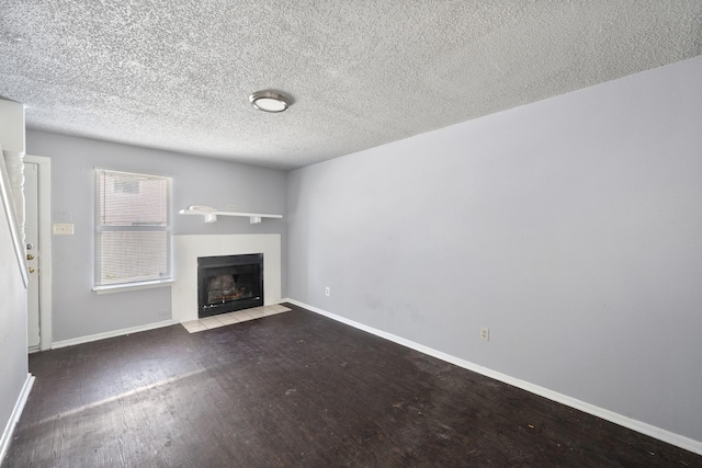 unfurnished living room with baseboards, a textured ceiling, a fireplace with flush hearth, and wood finished floors