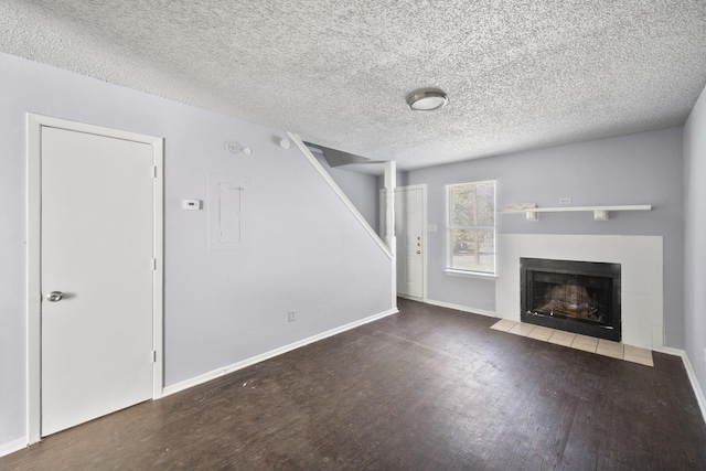 unfurnished living room with baseboards, a textured ceiling, wood finished floors, and a fireplace