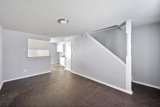 unfurnished living room with stairway, baseboards, dark wood-style flooring, and a textured ceiling