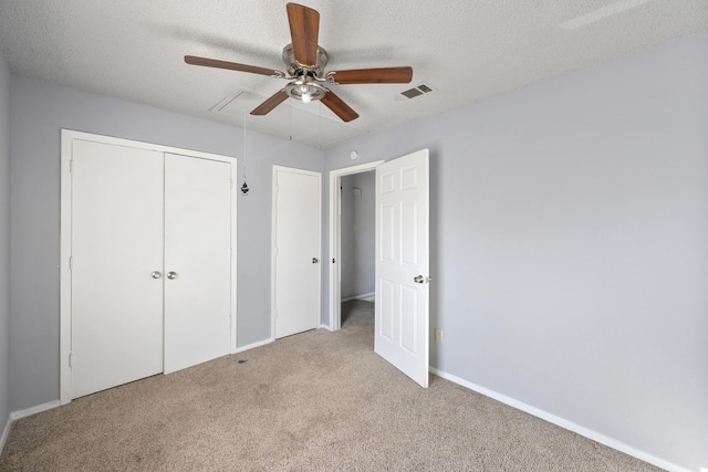 unfurnished bedroom featuring carpet flooring, ceiling fan, baseboards, visible vents, and a closet