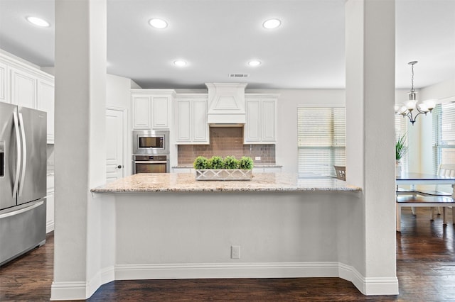 kitchen with decorative backsplash, white cabinetry, appliances with stainless steel finishes, and custom exhaust hood