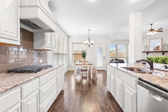 kitchen with appliances with stainless steel finishes, a sink, premium range hood, white cabinets, and dark wood-type flooring