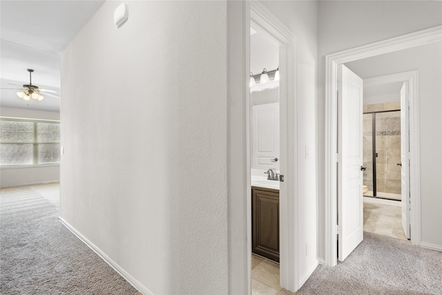 hallway with baseboards, light carpet, and a sink