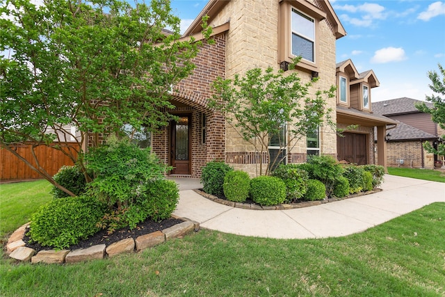 view of front facade featuring fence, driveway, a front lawn, and brick siding