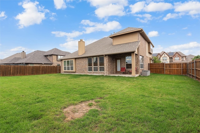 rear view of house featuring a chimney, a lawn, a patio area, brick siding, and a fenced backyard