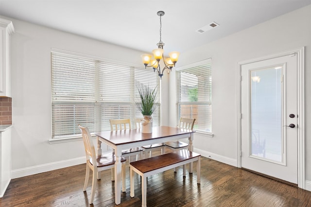 dining room featuring baseboards, visible vents, wood finished floors, and a chandelier