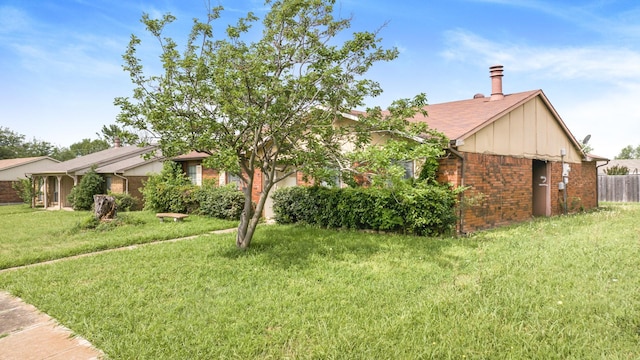view of front of home featuring fence, board and batten siding, a front yard, and brick siding