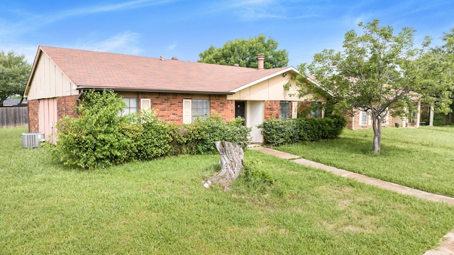 ranch-style house with brick siding, cooling unit, a shingled roof, and a front yard