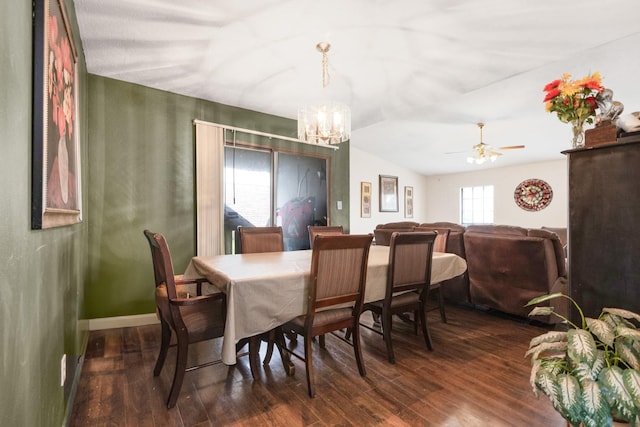 dining space with dark wood finished floors, ceiling fan with notable chandelier, and vaulted ceiling