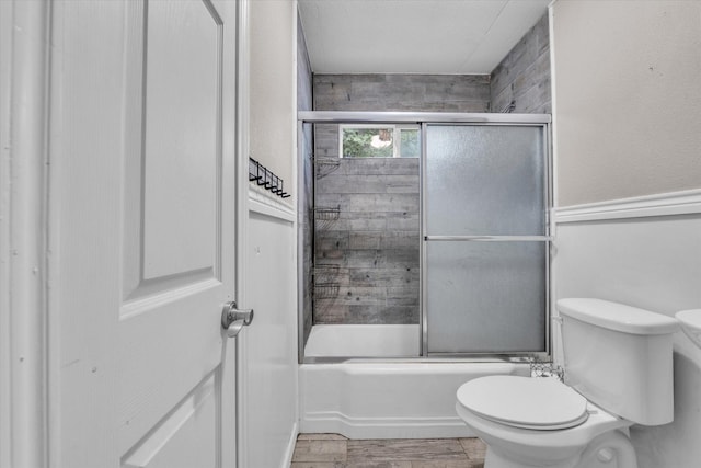 full bathroom with toilet, wood finished floors, and bath / shower combo with glass door