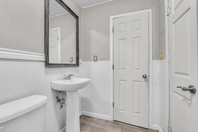 half bath featuring a sink, wood finished floors, and toilet
