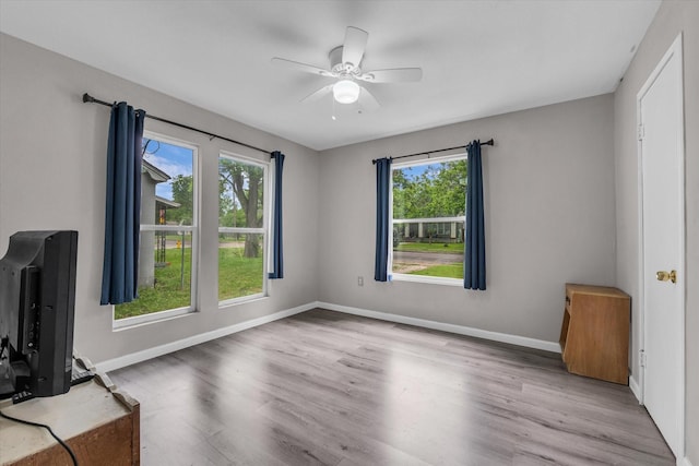 interior space with baseboards, a ceiling fan, and wood finished floors