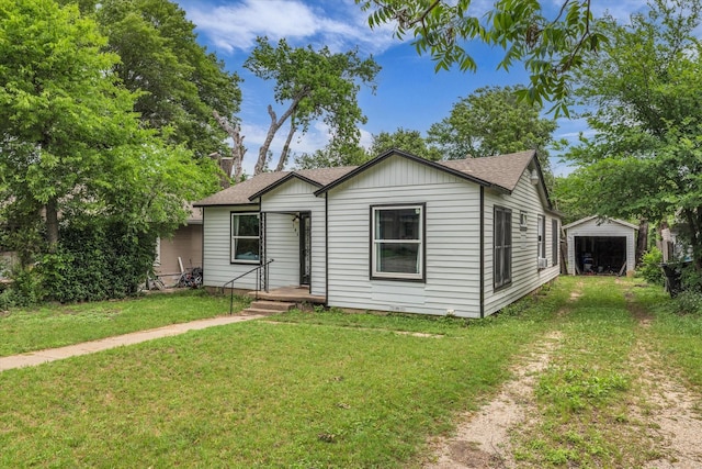 bungalow-style house with roof with shingles, an outbuilding, driveway, and a front yard