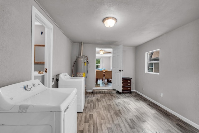 clothes washing area featuring independent washer and dryer, laundry area, baseboards, and light wood-style floors
