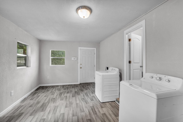 laundry room with laundry area, light wood-style floors, baseboards, and washing machine and dryer