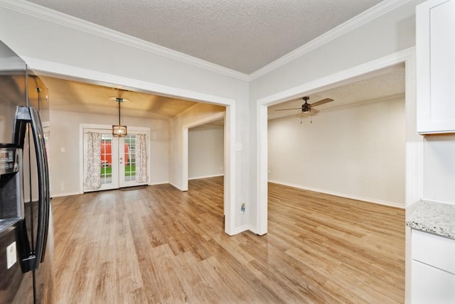 unfurnished living room featuring light wood-type flooring, ornamental molding, a textured ceiling, and a ceiling fan