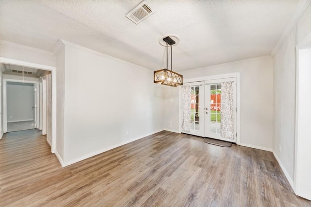 unfurnished dining area featuring crown molding, french doors, baseboards, wood finished floors, and visible vents