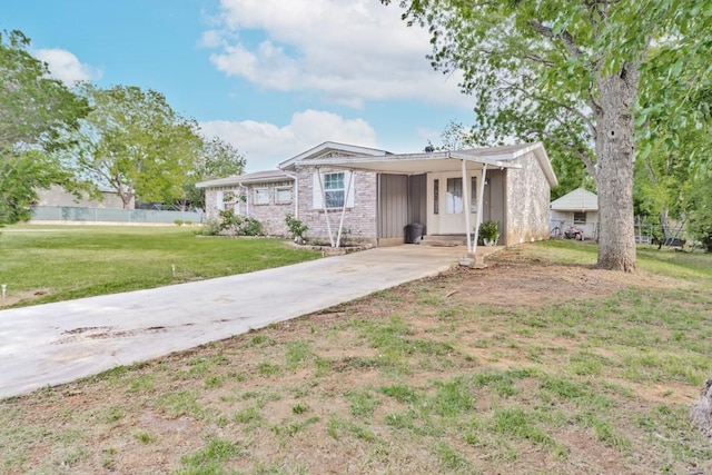 view of front facade featuring concrete driveway, fence, a front yard, and a carport