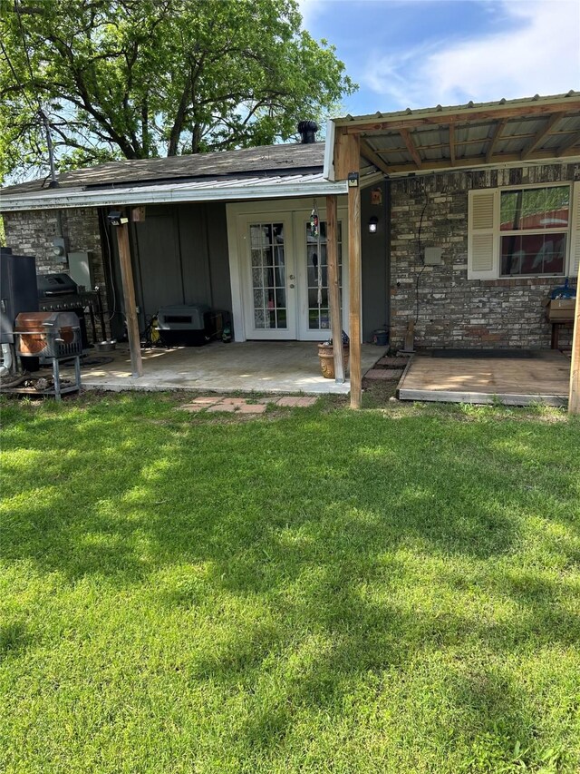 back of house featuring a lawn, board and batten siding, a patio area, and french doors