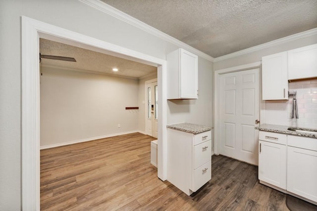 kitchen with wood finished floors, light stone counters, a textured ceiling, and white cabinetry