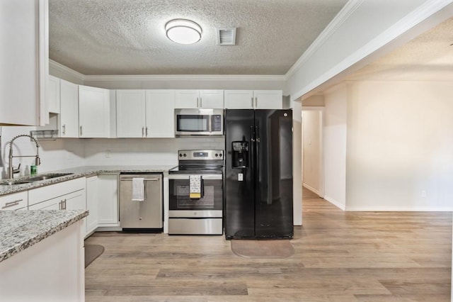 kitchen with a sink, a textured ceiling, appliances with stainless steel finishes, and white cabinets