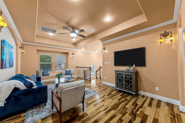 living area featuring a tray ceiling, wood finished floors, and visible vents