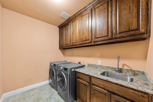 clothes washing area featuring visible vents, washing machine and clothes dryer, cabinet space, a sink, and baseboards