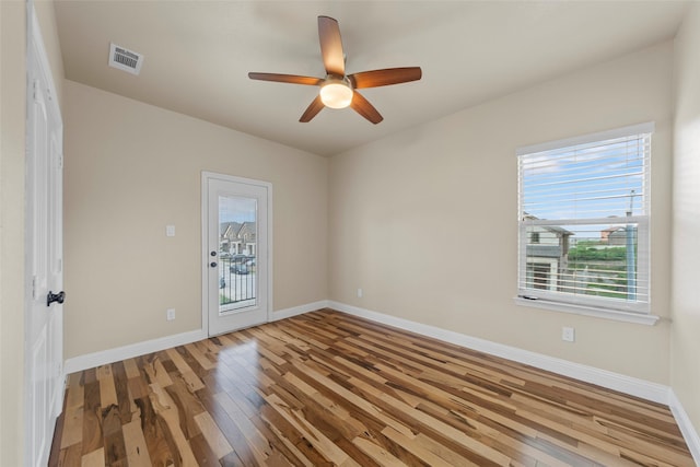 spare room with ceiling fan, baseboards, visible vents, and wood finished floors