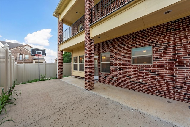 view of patio featuring fence and a balcony