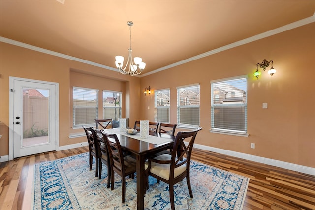 dining room featuring crown molding, baseboards, wood finished floors, and a notable chandelier