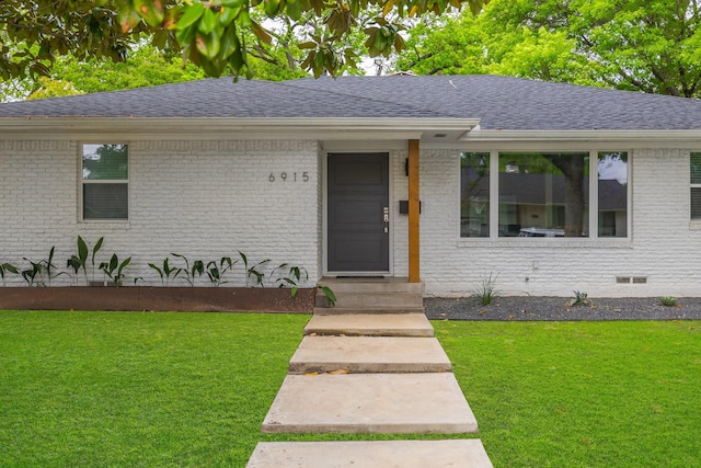 ranch-style home featuring brick siding, a shingled roof, and a front lawn