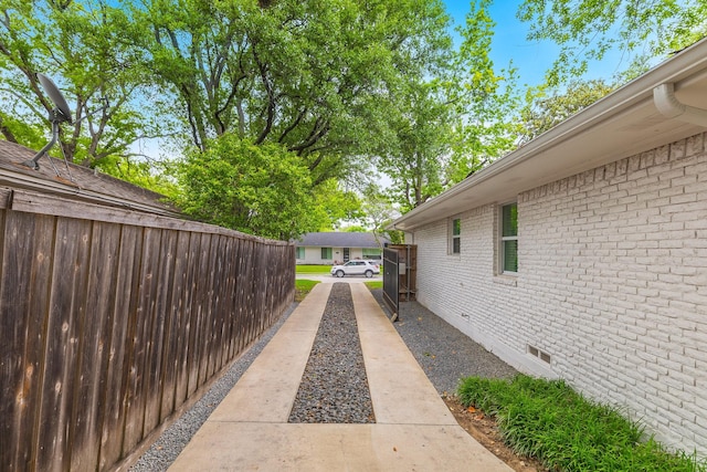 view of property exterior featuring brick siding, crawl space, and fence