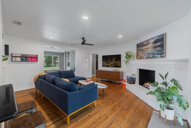 living room with a ceiling fan, visible vents, a fireplace, wood finished floors, and recessed lighting