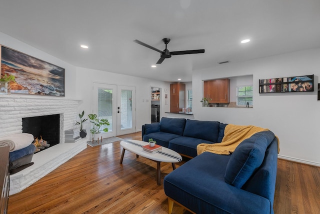 living area with ceiling fan, a brick fireplace, recessed lighting, and wood finished floors
