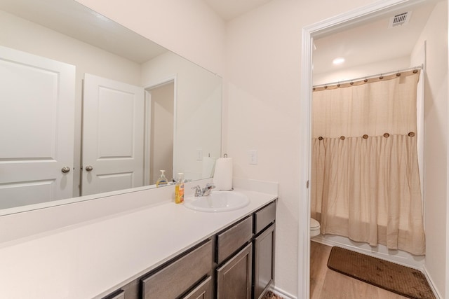 full bath with visible vents, shower / tub combo with curtain, vanity, wood finished floors, and toilet