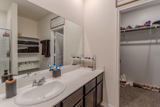 bathroom with vanity, a shower with door, and a spacious closet