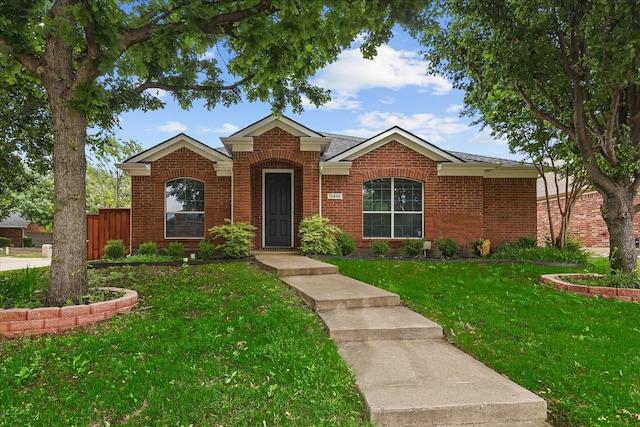view of front of home featuring brick siding, a shingled roof, fence, and a front yard