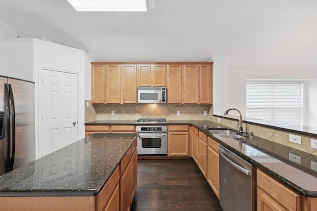 kitchen with decorative backsplash, appliances with stainless steel finishes, a sink, dark wood-style floors, and dark stone counters