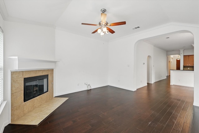 unfurnished living room featuring arched walkways, a ceiling fan, dark wood finished floors, and a tile fireplace