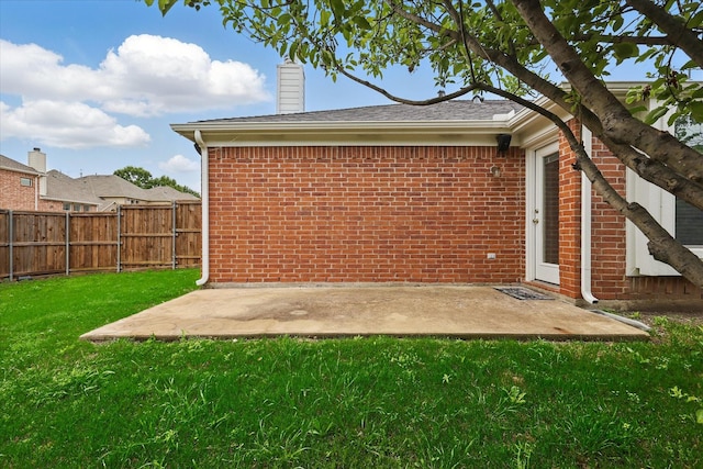 rear view of house featuring fence, a chimney, brick siding, a patio area, and a yard