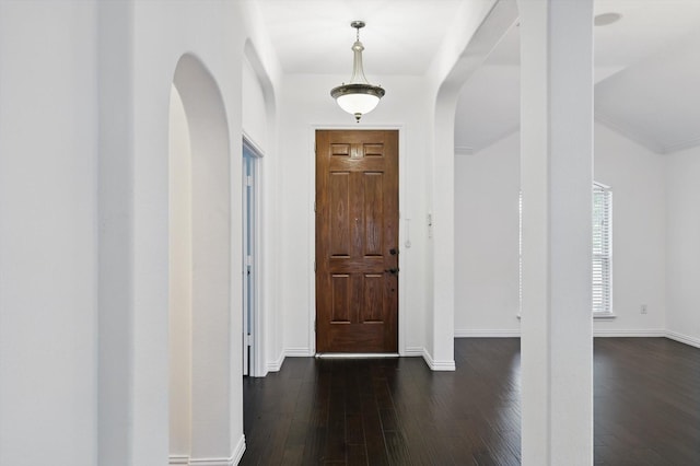 entryway with arched walkways, baseboards, and dark wood-style flooring