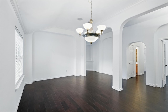 unfurnished dining area featuring crown molding, wood finished floors, baseboards, a chandelier, and arched walkways