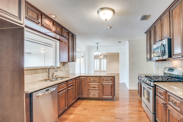 kitchen featuring backsplash, stainless steel appliances, a sink, and light wood-type flooring