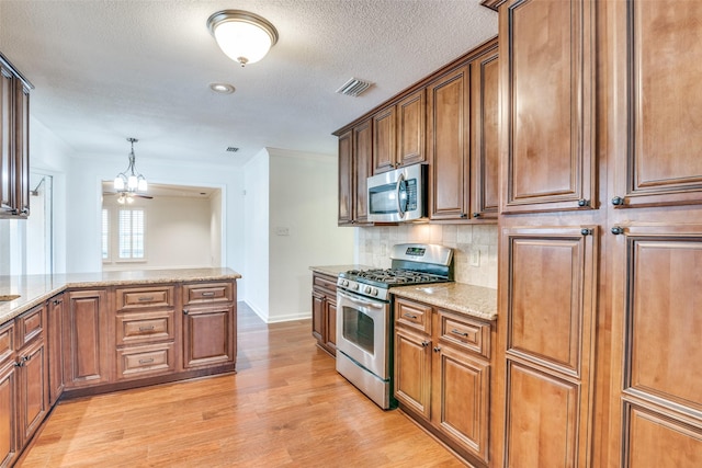 kitchen with light stone counters, appliances with stainless steel finishes, an inviting chandelier, light wood-style flooring, and tasteful backsplash