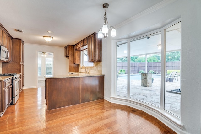 kitchen featuring visible vents, ornamental molding, light stone countertops, a sink, and stainless steel appliances
