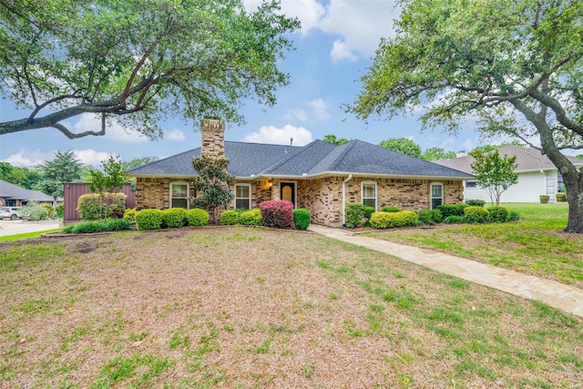 ranch-style house with a chimney, a front lawn, and brick siding