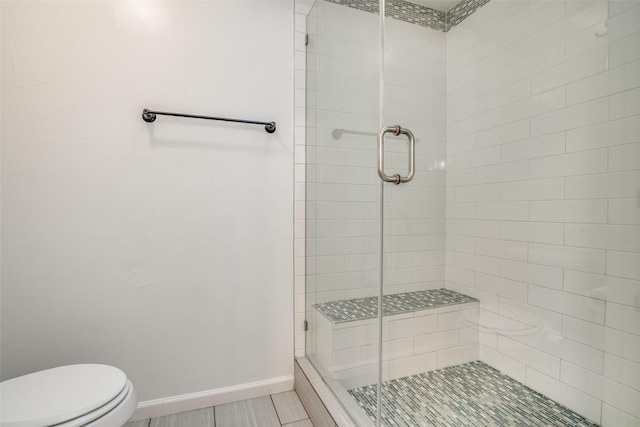 full bath with baseboards, a stall shower, and toilet