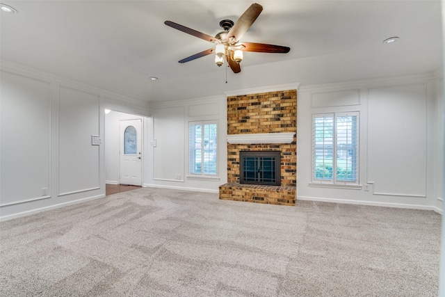 unfurnished living room featuring a ceiling fan, a wealth of natural light, carpet, and a decorative wall